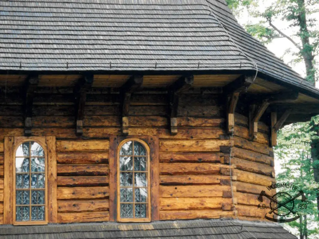 Dom z bali z dachem krytym gontem drewnianym i oknami zwieńczonymi łukiem